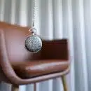 silver round pendant on brown wooden chair